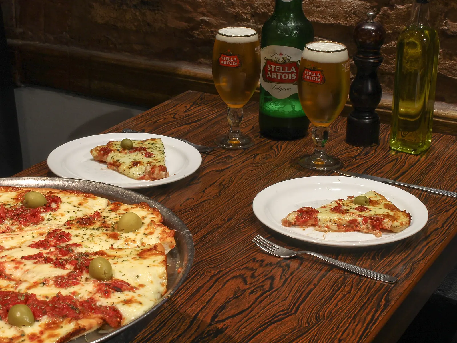 Pizza de muçarela com azeitonas e cerveja em uma mesa da Don Boedo